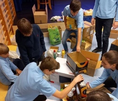 Uczniowie pakujący produkty do kartonowych pudeł