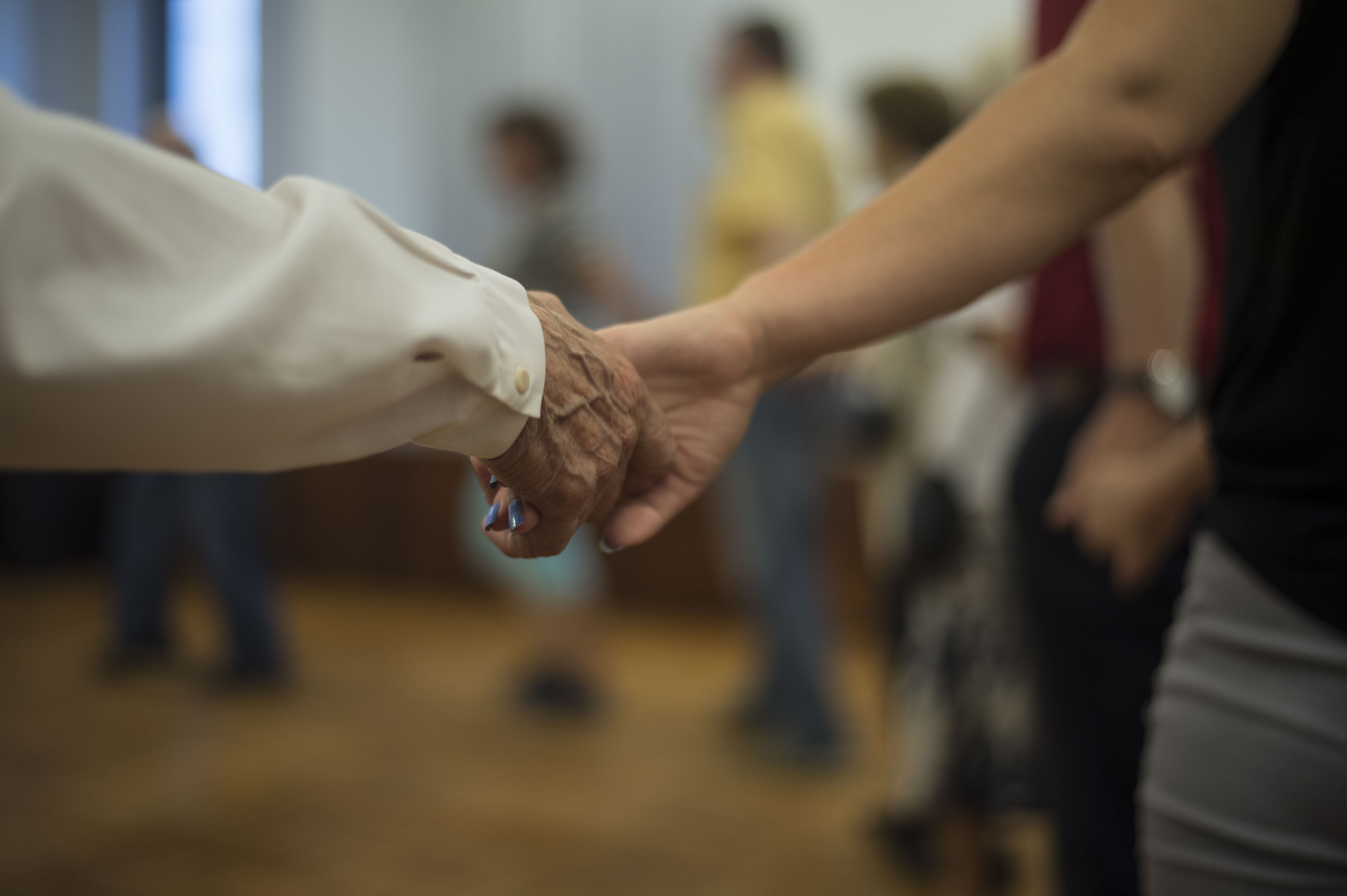 Seniorzy trzymający się za ręce podczas zajęć tanecznych