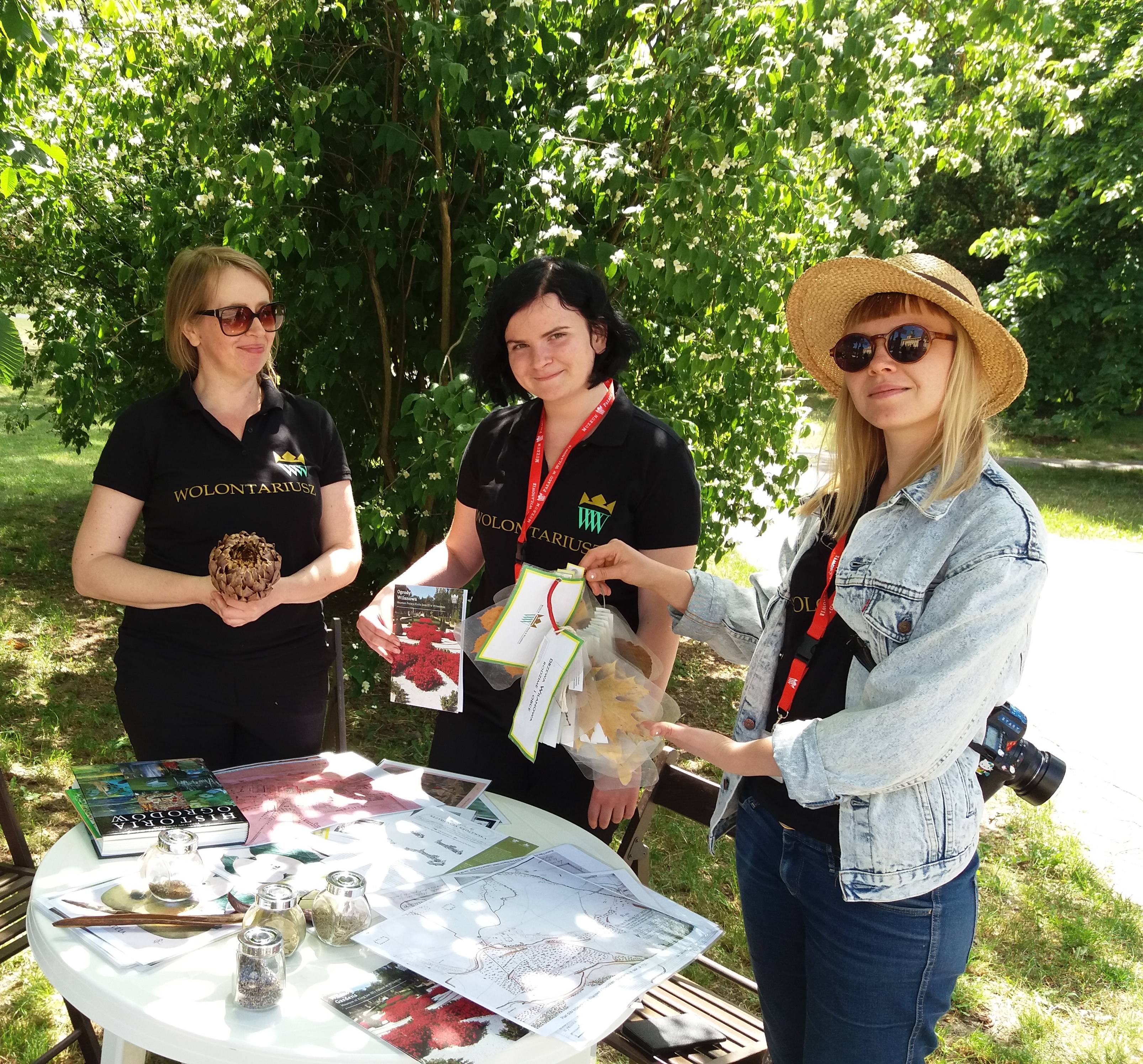 Trzy wolontariuszki prezentują materiały Muzeum w Wilanowie