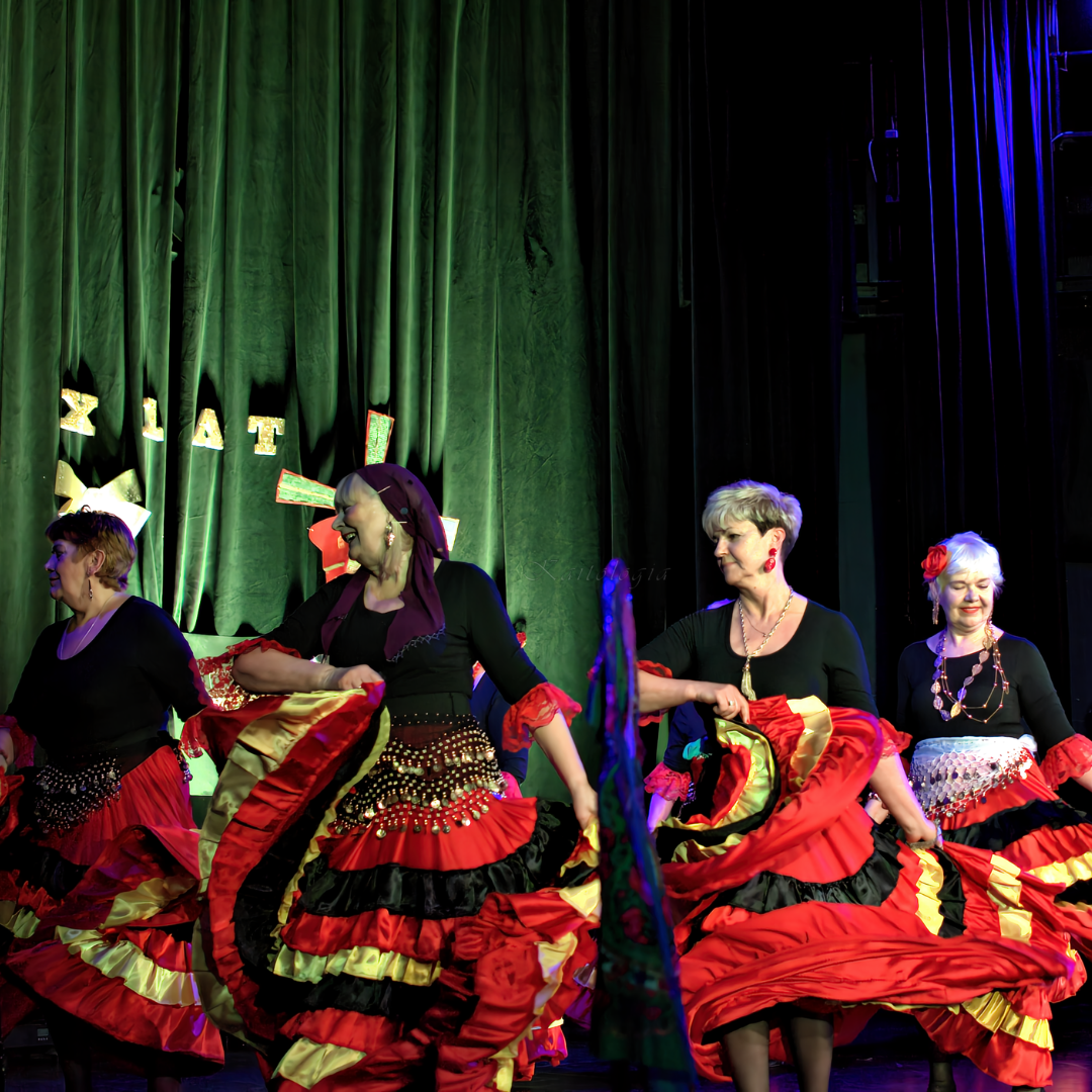 Cztery tancerki w sukniach wykonują układ na scenie.