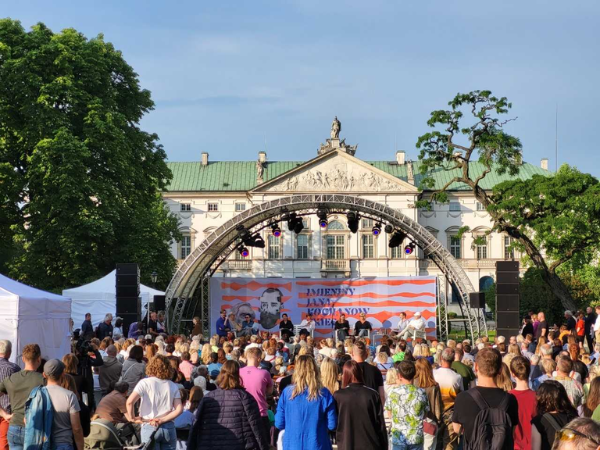 Tłum ludzi stojących pod sceną z napisem Imieniny Jana Kochanowskiego 