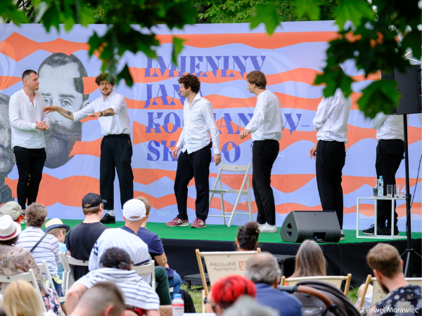 Sześciu mężczyzn w białych koszulach stojących na scenie 