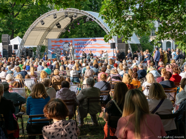Grupa ludzi siedzących na leżakach przed sceną 