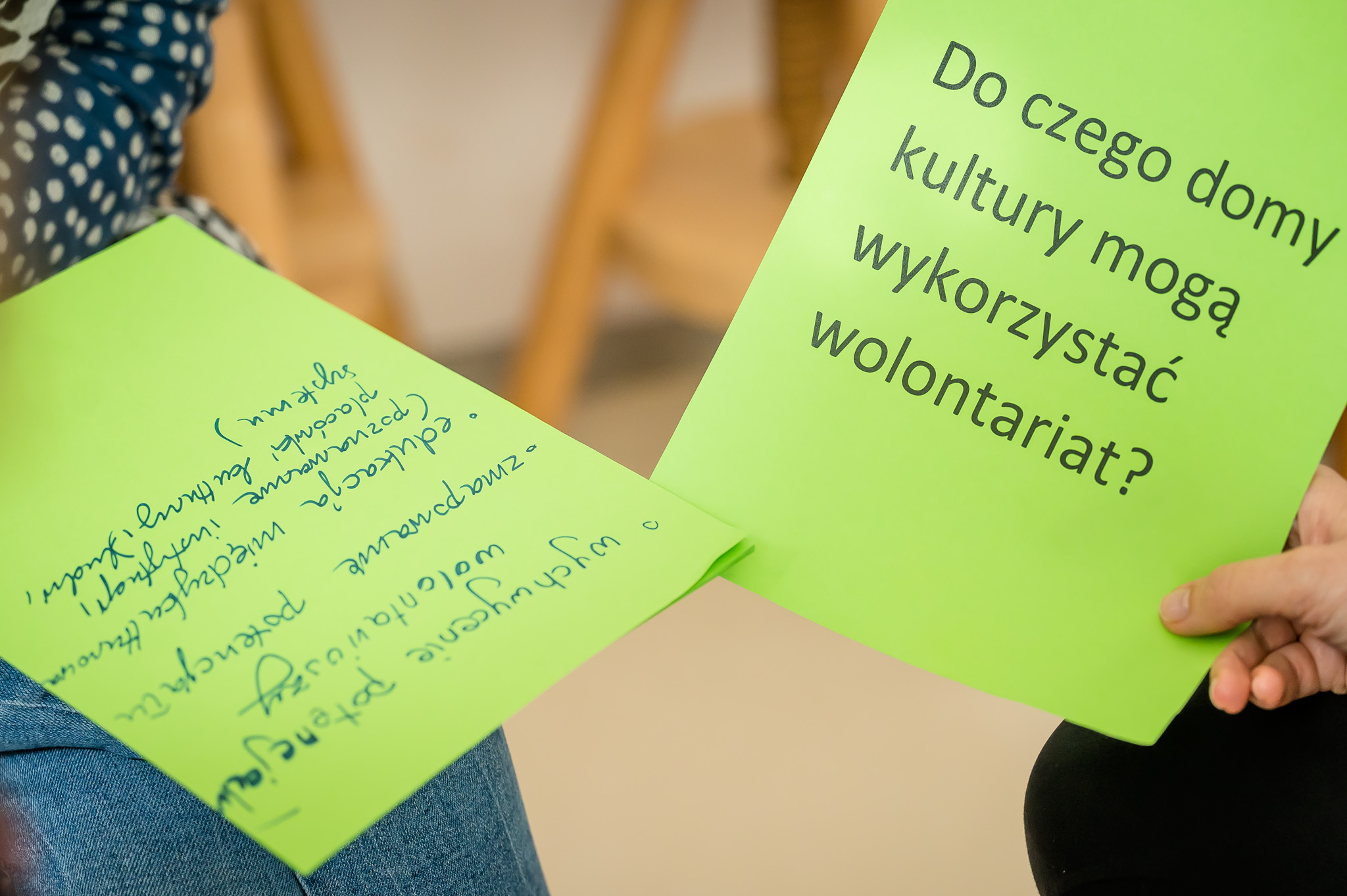 kartka z napisem "do czego domy kultury mogą wykorzystać wolontariat?" trzymana w ręku, na kolanach drugiej osoby kartka z wypracowanymi pomysłami