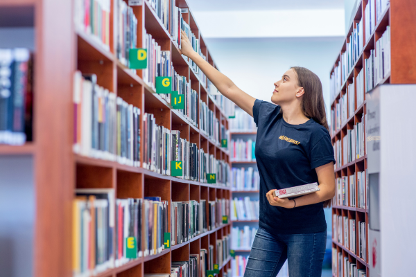Wolontariuszka układająca książki w bibliotece.