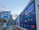 Znak przystanku tramwajowego. Obok tramwaj z wyklejonymi oknami plakatami z napisami: wolontariat? to niesienie pomocy oraz wolontariat? to sposób na spędzanie czasu wolnego