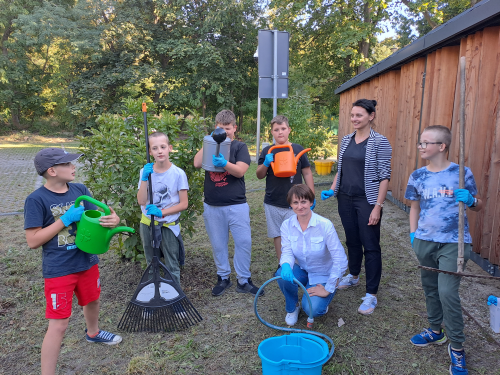 Zdjęcie wolontariuszy młodzieżowych z narzędziami ogrodniczymi przy pracy w ogrodzie społecznym