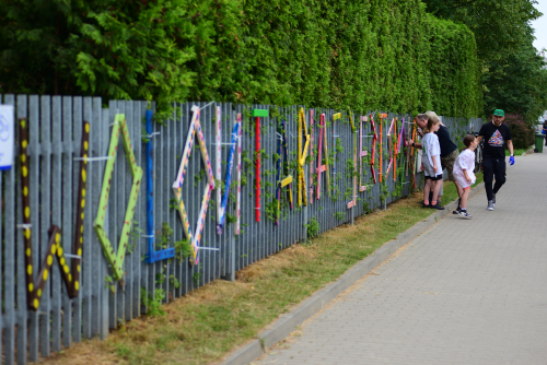 Zdjęcie prezentujące napis "Wolontariat jest spoko" wykonany z pomalowanych kolorowo desek, umieszczony na ogrodzeniu amfiteatru w parku