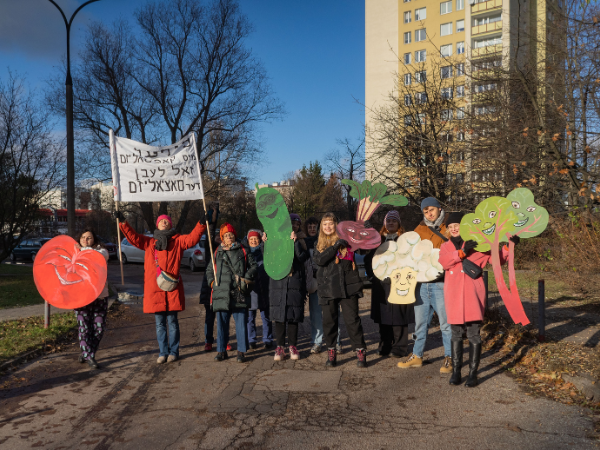 Grupa ludzi stojąca w parku i trzymająca wycięte z papieru warzywa.