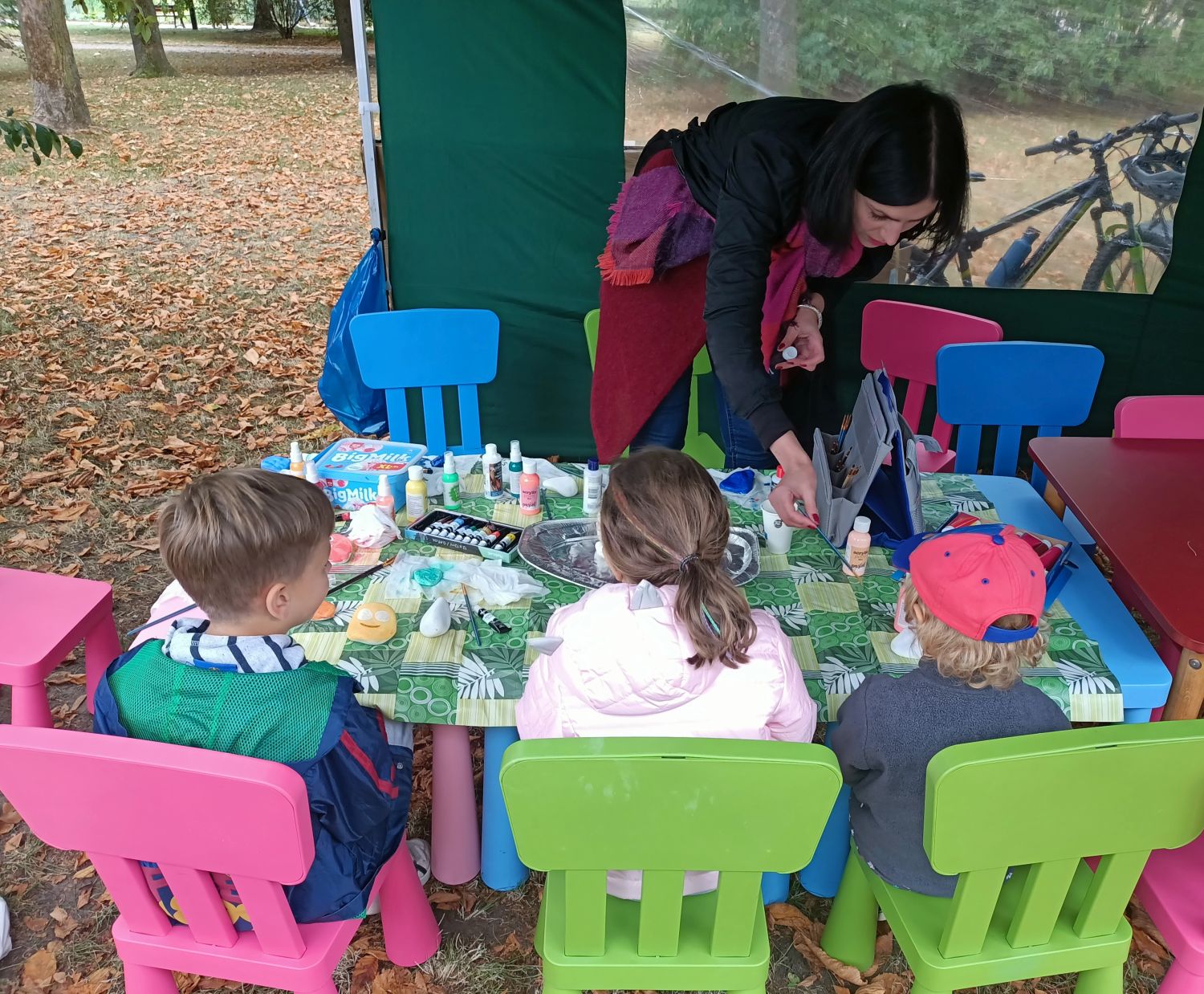 Wolontariuszka pokazuje dzieciom, jak malować kamienie podczas "Wolontariackiego Pikniku Rodzinnego" 