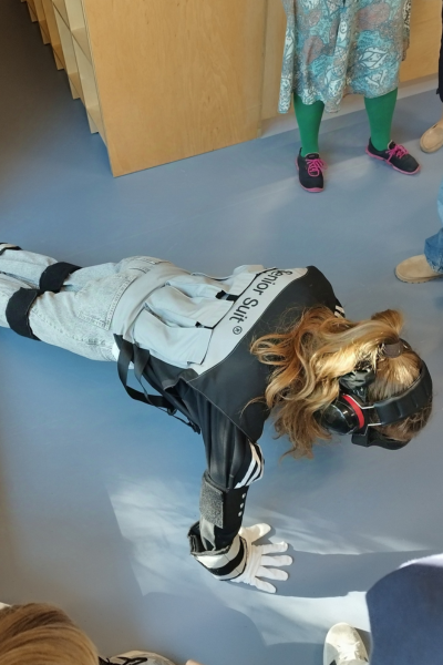 Kobieta wykonująca pompki w kombinezonie symulującym starość.