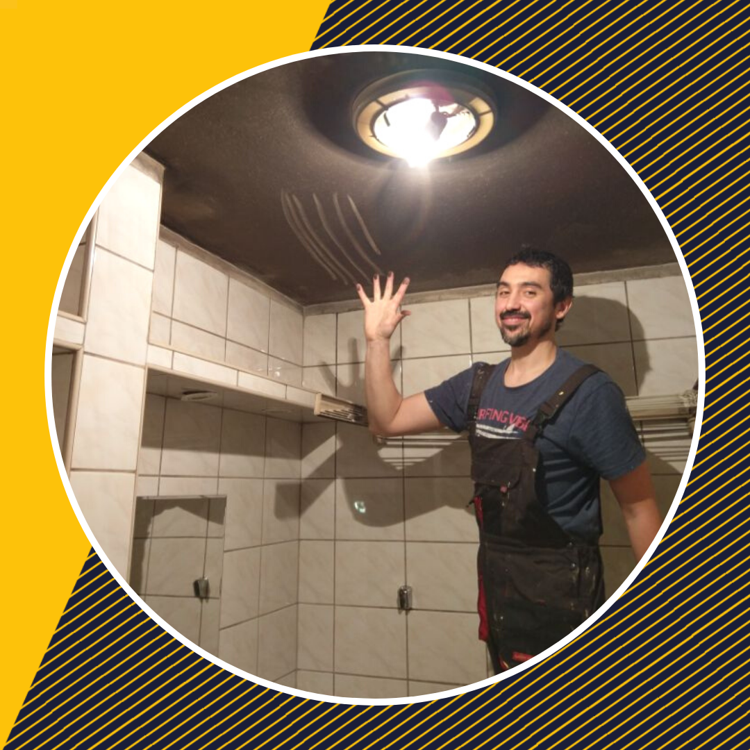 Wolontariusz Caritas Diecezji Warszawsko-Praskiej podczas remontu mieszkania. Jest w łazience, uśmiecha się i pokazuje dłoń ze śladami brudu z sufitu.