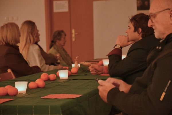 Sąsiedzkie spotkanie świąteczne. Przy wspólnym stole zgromadzeni są uczestnicy i uczestniczki.