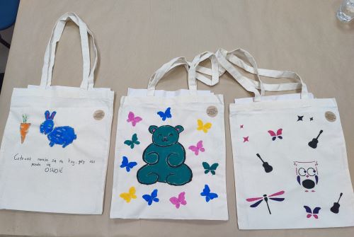 Zdjęcie trzech toreb lnianych ozdobionych własnoręcznie przez wolontariuszy; na jednej z toreb napis: Człowiek naraża się na łzy gdy raz pozwoli się oswoić