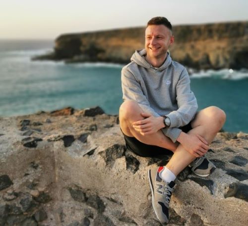 Daniel Plata - zdjęcie portretowe, w tle morze i kamienisty brzeg